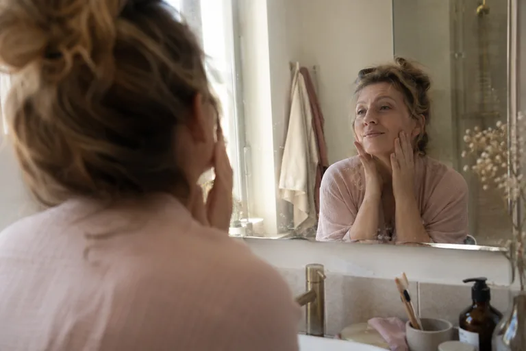 Gros plan d’un miroir de salle de bain avec le reflet flou d’une femme qui parle doucement