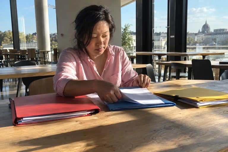 Une femme trie des dossiers sur une table de cantine
