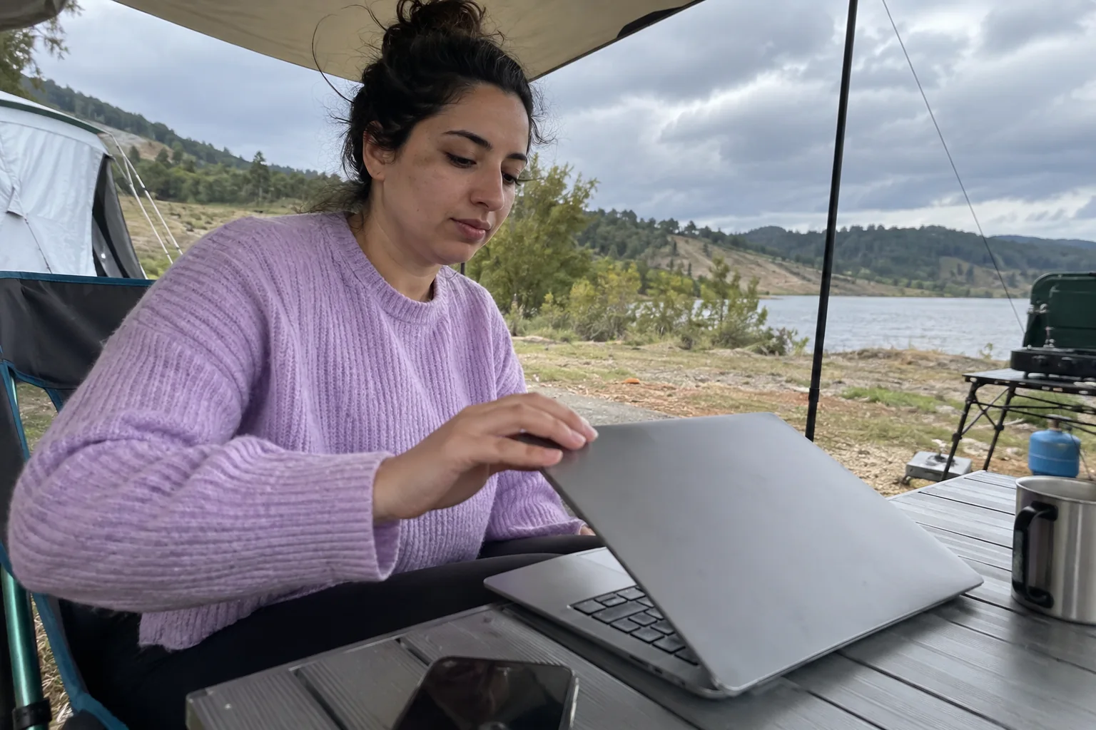 Une femme ferme son ordinateur sous un auvent