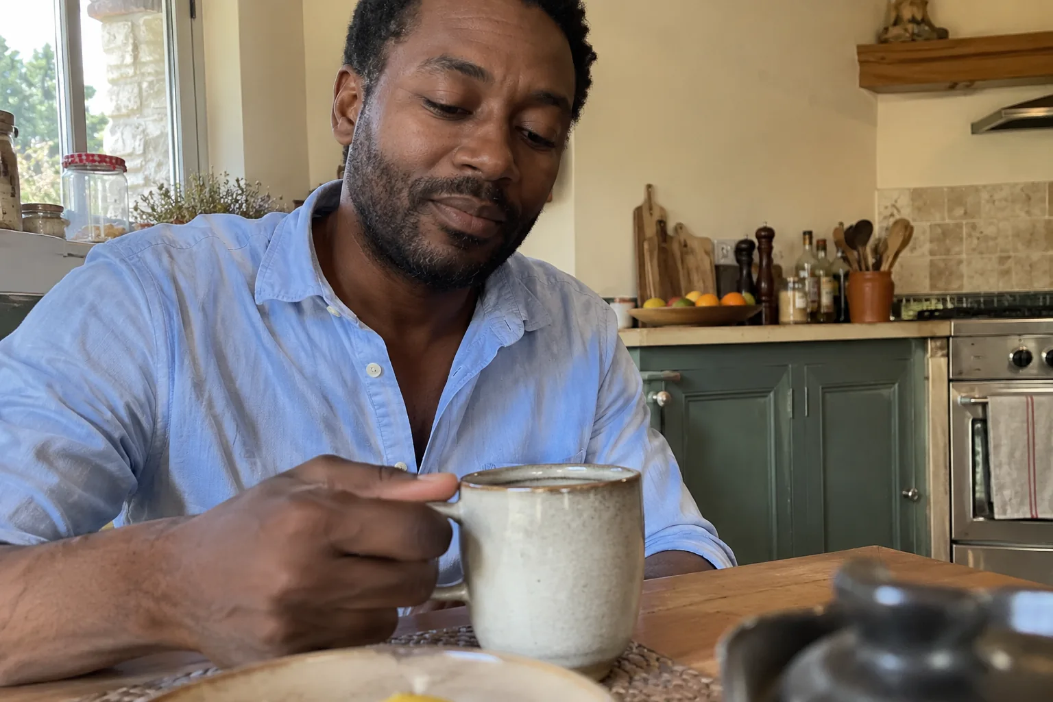 Un homme tient une tasse dans sa cuisine