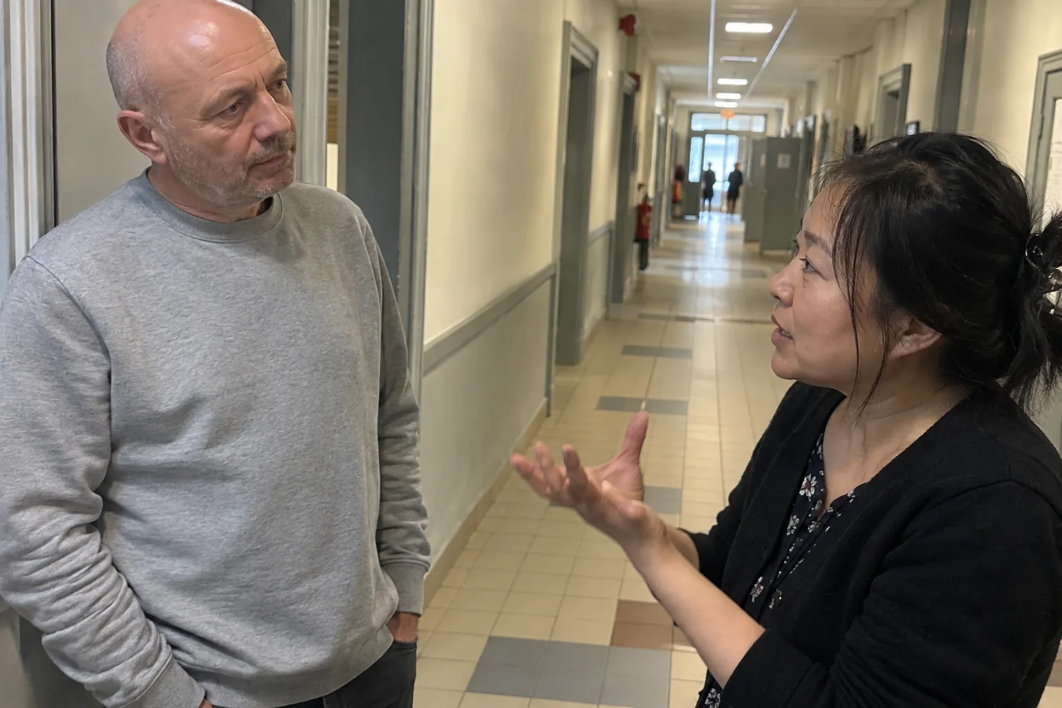 Un homme écoute une collègue dans un couloir