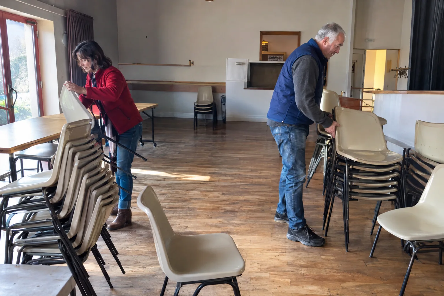 Deux bénévoles rangent des chaises