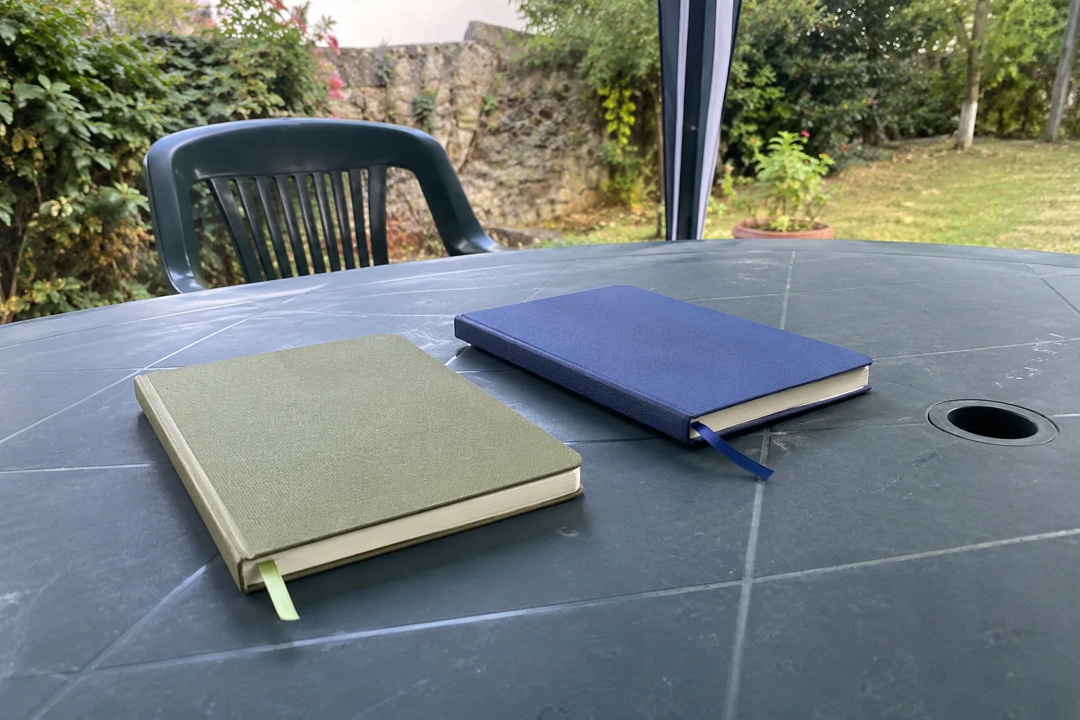Deux carnets fermés sur une table de jardin
