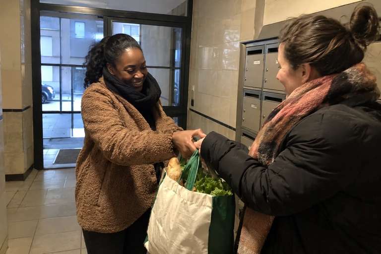 Deux femmes se passent un sac de courses dans un hall