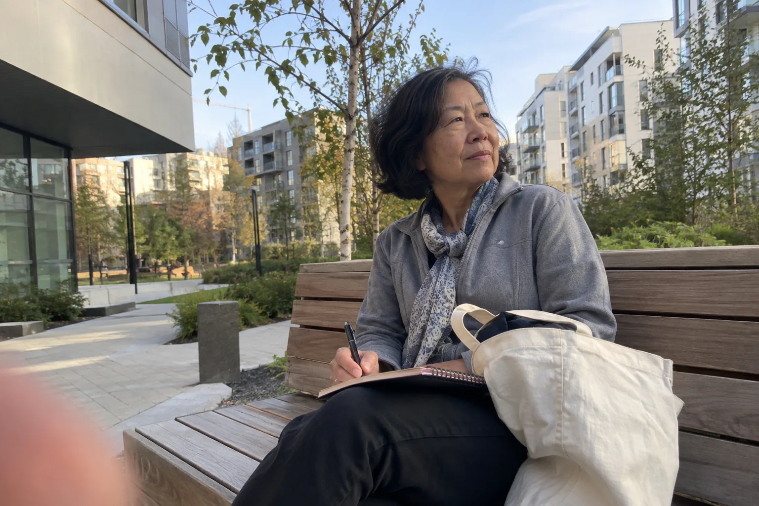 Une femme observe un nouveau quartier depuis un banc