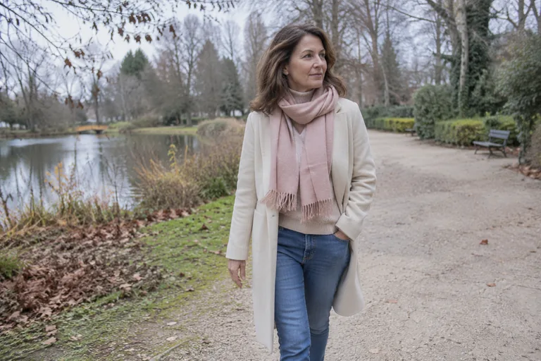 Une femme marche seule dans un parc, manteau ouvert, air pensif et doux
