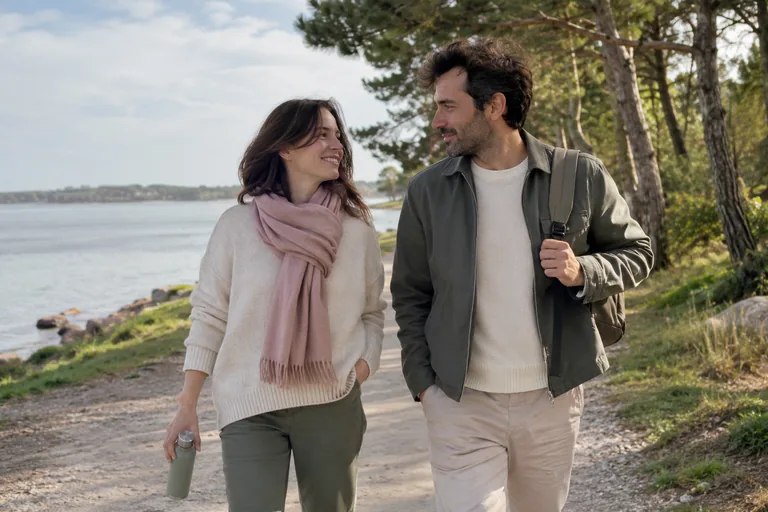 Deux adultes marchent ensemble sur un chemin au bord de l’eau.