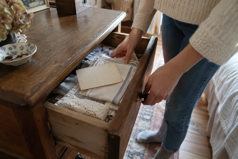 Une personne ouvre un tiroir contenant du linge plié et des cartes.