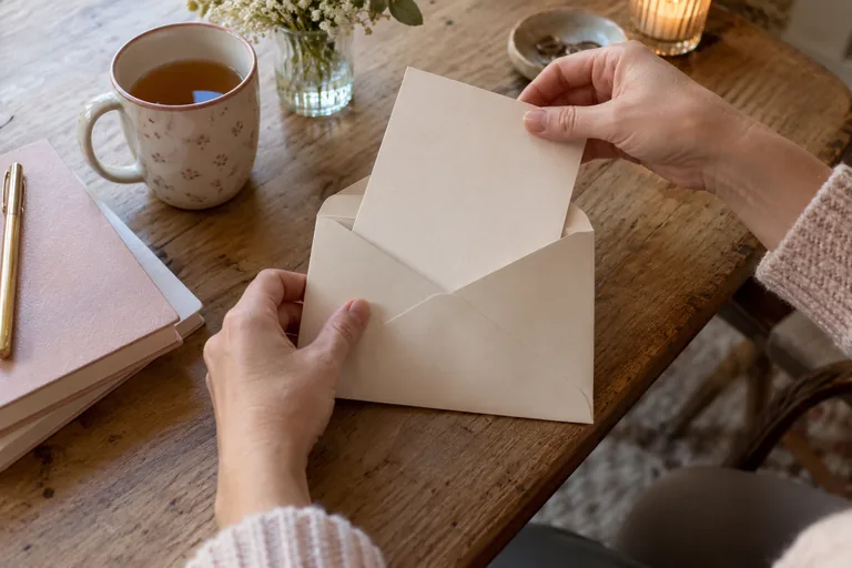 Des mains plient une feuille écrite avant de la glisser dans une enveloppe