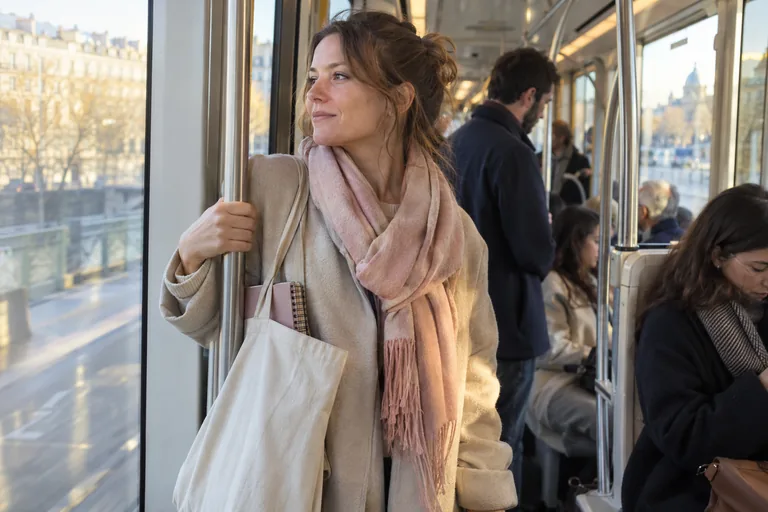 Une femme dans le tram le matin, carnet rangé dans son sac, l’air plus calme